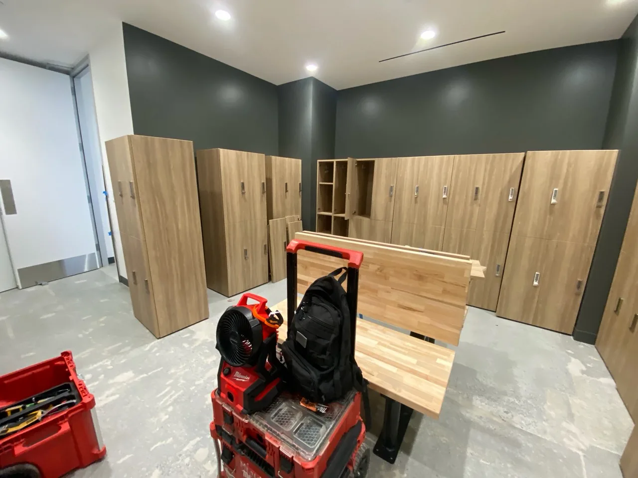 A row of fully assembled, wall-mounted wood-finish lockers installed in a locker room.
