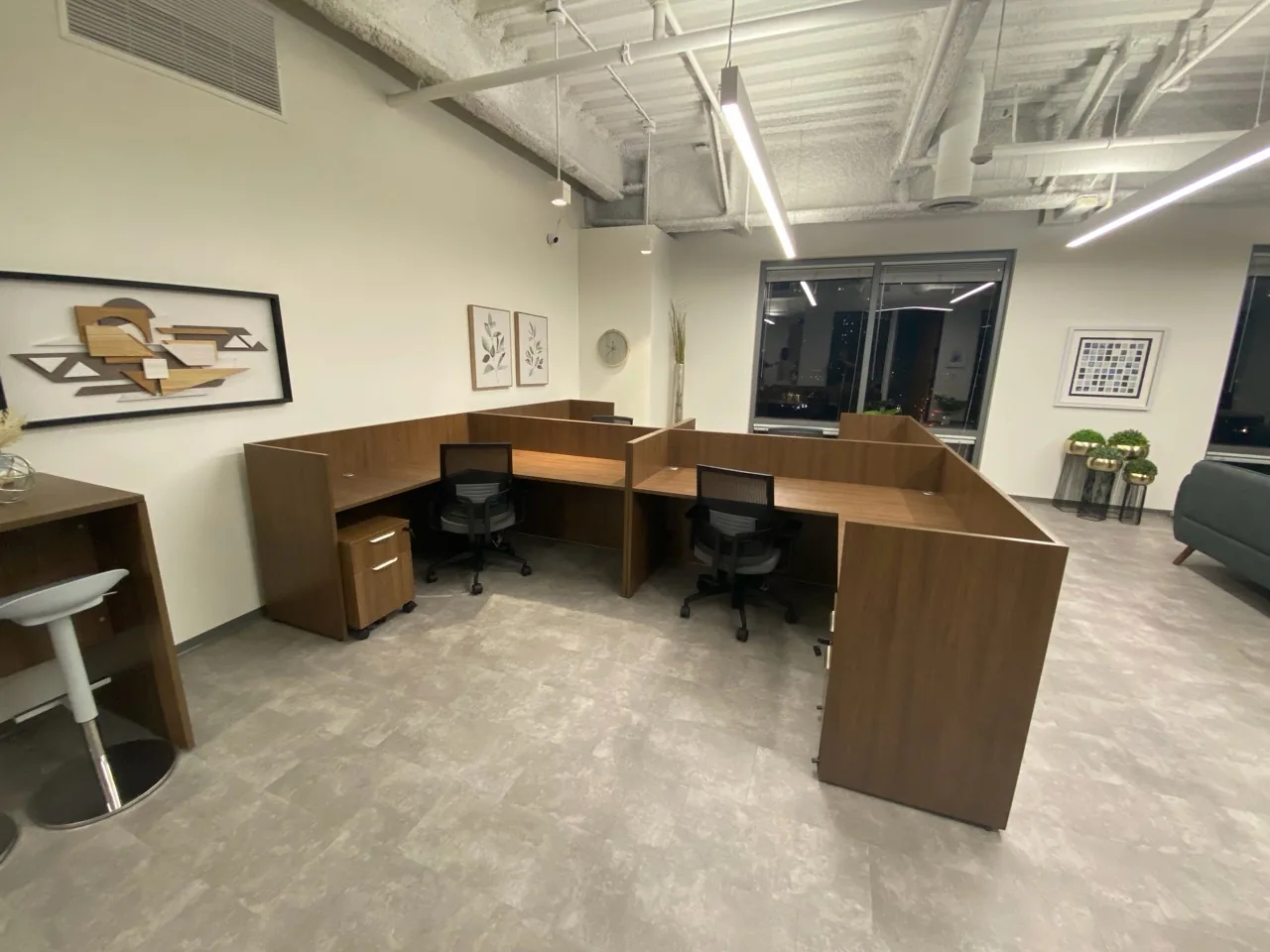 A finished office workstation area with two L-shaped desks, task chairs, and wall art, fully assembled and arranged.